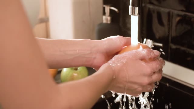 Washing-Fruits-With-Clean-Water-In-Kitchen-Closeup