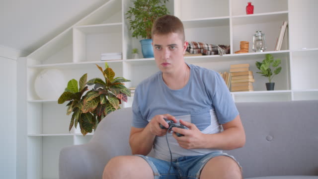 Closeup-portrait-of-adult-attractive-caucasian-man-playing-video-games-using-game-console-being-nervous-sitting-on-couch-indoors