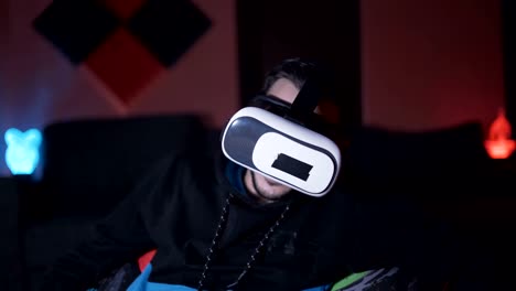 Man-sitting-on-sofa-at-home-playing-games-and-watching-movies-with-VR-glasses