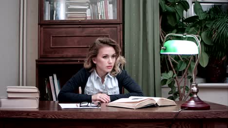 Mujer-frustrada-mirando-con-impaciencia-los-papeles-y-los-libros-en-su-escritorio-golpeando-sus-puños-sobre-la-mesa