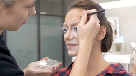 A-professional-make-up-artist-draws-body-art-on-the-face-of-the-model.-Preparing-for-a-beauty-contest.