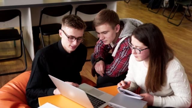 Junge-männliche-Schüler-zeigen-etwas-zu-seinen-Freunden-auf-einem-laptop