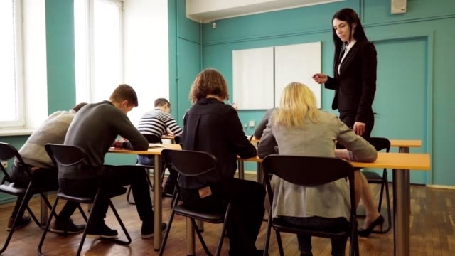 Woman-teacher-check-students-progress-during-a-lesson-in-classroom