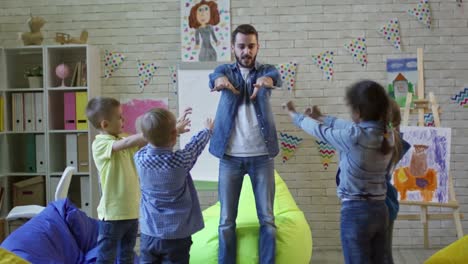 Profesor-y-los-niños-haciendo-ejercicios-físicos-en-el-Kinder