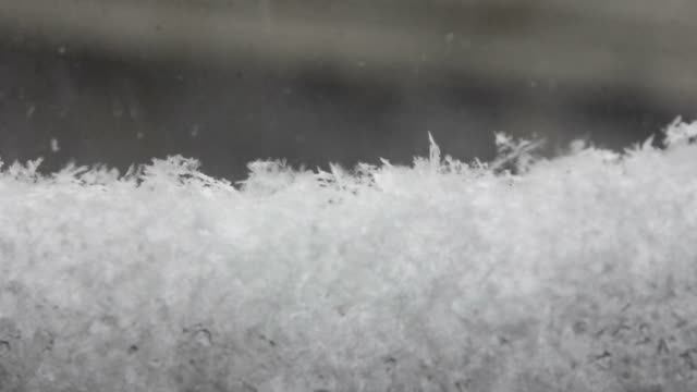 Time-lapse-snow-falling-and-gathering-on-window-snowflakes-close-up