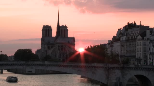 Ein-Boot-vorbei-an-Notre-Dame-den-Sonnenuntergang-im-Hintergrund