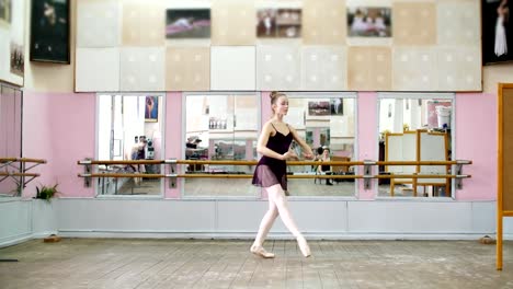in-dancing-hall,-Young-ballerina-in-black-leotard-performs-pas-courru-,-pointe-,-She-is-moving-through-the-ballet-class-elegantly