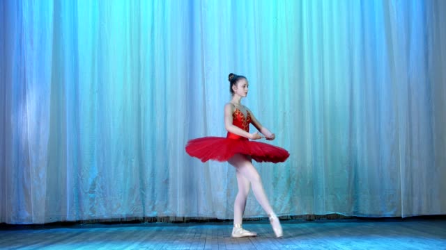 ballet-rehearsal,-on-the-stage-of-the-old-theater-hall.-Young-ballerina-in-red-ballet-tutu-and-pointe-shoes,-dances-elegantly-certain-ballet-motion,-tour-fouitte