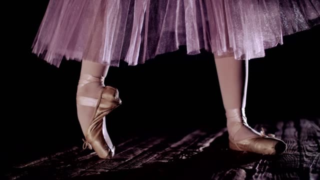 close-up,-in-rays-of-spotlight,-on-stage-of-old-theater-hall.-ballerina-in-white-ballet-skirt,-raises-on-toes-in-pointe-shoes,-performs-elegantly-a-certain-ballet-exercise,-pointe-,tendu