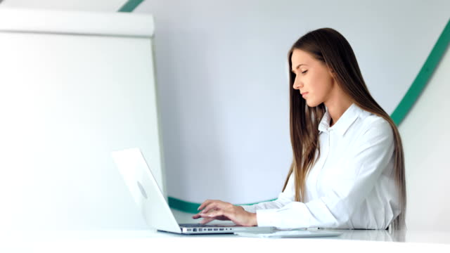 Schöne-geschäftsfrau-mit-Laptop-im-weißen-Büro-arbeiten