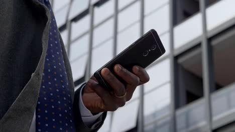 Black-business-man's-hand-typing-on-smartphone.-Business,-technology,