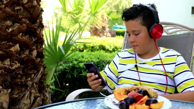 Niño-con-auriculares-con-smartphone-en-el-jardín