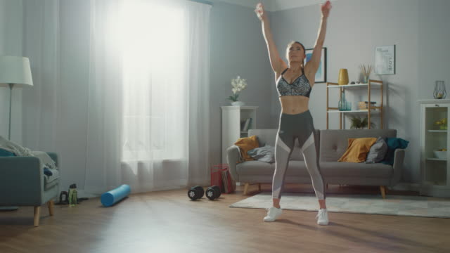 Schöne-vollbusige-Fitness-Mädchen-in-einem-sportlichen-Top-ist-tun-Stretching-Yoga-Übungen-in-ihr-helles-und-geräumiges-Wohnzimmer-mit-minimalistisches-Interieur.