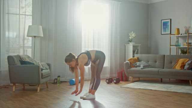 Schöne-formschöne-Fitness-Mädchen-in-einem-sportlichen-Top-ist-tun-Stretching-Yoga-Übungen-in-ihr-helles-und-geräumiges-Wohnzimmer-mit-modernem-Interieur.