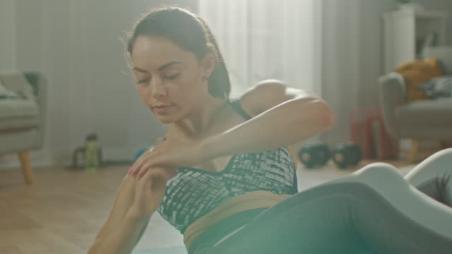 Slow-Motion-Close-Up-Shot-of-a-Beautiful-Confident-Busty-Fitness-Female-in-an-Athletic-Top-is-Doing-Abdominal-Workout-in-Her-Bright-and-Spacious-Apartment-with-Minimalistic-Interior.