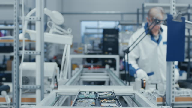 Time-Lapse-of-Electronics-Factory-Workers-Assembling-Smartphone-Circuit-Boards-by-Hand-While-they-Move-on-the-Assembly-Line.-High-Tech-Factory-Facility.