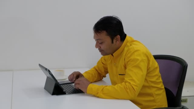 Mann-arbeiten-auf-einem-Tisch-mit-seinem-touch-Screen-Tastatur-Tablette-und-erhält-einen-Anruf-auf-seinem-Smartphone,-dauert-es-und-lächelt