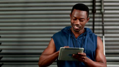 Fit-man-using-tablet-and-smiling-at-the-camera