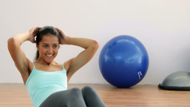 Fit-brunette-doing-sit-ups-on-exercise-mat