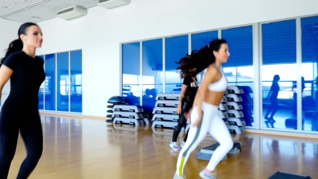 Junge-sportliche-Frauen-trainieren-die-Step-Aerobic-im-Fitnessstudio