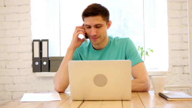 Mann-auf-Smart-Phone-in-seinem-Büro-im-Gespräch