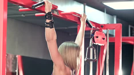 Fit-sporty-woman-doing-body-lifting-pull-chin-up-exercises-in-gym