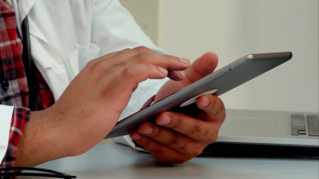 Male-doctor-hands-using-digital-tablet