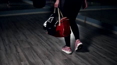 Closeup-view-of-woman's-legs-walking-in-a-boxing-club.-Young-female-boxer-putting-down-her-bag-and-taking-out-a-bottle-with-water-preparing-for-training.-Shot-in-4k
