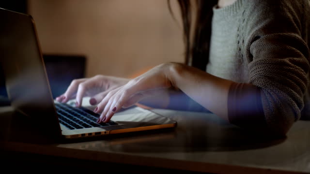 Vista-primer-plano-femenino-manos-escribiendo-en-el-portátil.-Mujer-morena-usando-la-computadora-sentado-en-la-mesa-de-noche