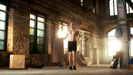Muscular-Fit-Man-Exercises-with-Jump-/-Skipping-Rope-in-a-Deserted-Factory-Hardcore-Gym.-He's-Sweaty-from-His-Cross-Fitness-Exhausting-Training.