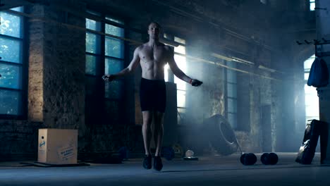 Athletic-Shirtless-Fit-Man-Exercises-with-Jump-/-Skipping-Rope-in-a-Deserted-Factory-Hardcore-Gym.-He's-Covered-in-Sweat-from-His-Intense-Fitness-Training.