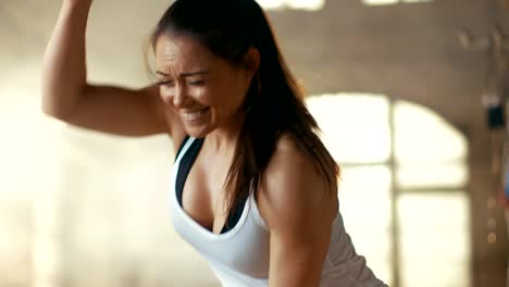 Athletic-Female-in-a-Gym-Exercises-with-Battle-Ropes-During-Her-Cross-Fitness-Workout/-High-Intensity-Interval-Training.-She's-Muscular-and-Sweaty,-Gym-is-in-Industrial-Building.