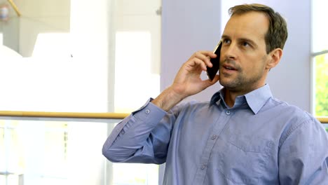 Männliche-Executive-telefonieren-mit-Handy-während-der-Arbeit-am-Schreibtisch-4k
