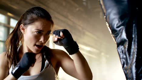 Mujer-combatiente-de-entrenamiento-con-saco-de-boxeo-su-pareja-lleva-a-cabo.-Ella-es-atlética-y-tiene-golpe-de-gran-alcance.