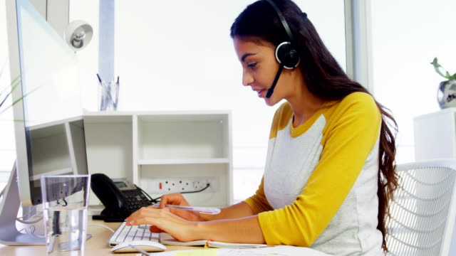 Ejecutivo-de-negocios-con-auriculares-usando-computadoras-en-el-escritorio-en-la-oficina-4k