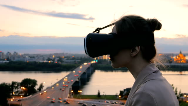Frau-nutzt-virtual-Reality-Brille-in-der-Stadt-nach-Sonnenuntergang