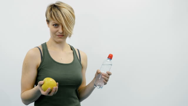 Mujer-con-manzana-y-agua-en-el-gimnasio