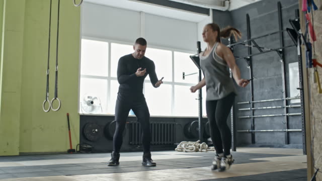 Entrenador-personal-motivación-mujer-durante-ejercicio-de-saltar-la-cuerda