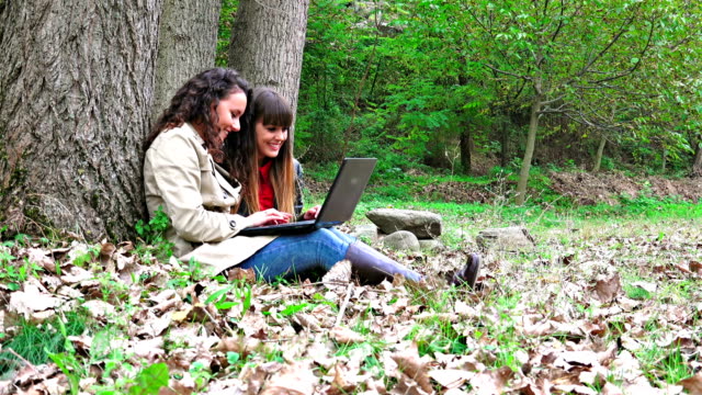 Happy-female-students-with-smartphone,-laptop,-tablet-in-the-park,-sony-steadycam-uhd-shoot,-stock-video