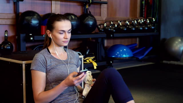 The-girl-is-listening-to-music-on-headphones-during-a-break-between-training-sessions