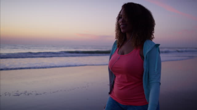 African-American-mujer-ejercicio-vistiendo-ropa-de-deporte-en-la-playa