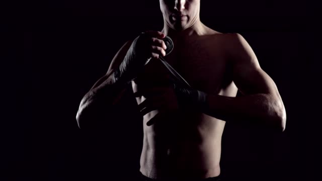 Männlicher-Boxer-wickelt-seine-Hände-mit-Handwrap.-Profi-Boxer-Bandagen-auf-seiner-Hand-wickeln.-Kämpfer,-die-Umhüllung-Hände-mit-Boxen-Wraps-in-der-Turnhalle