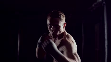 Boxeo-de-sombra-de-kickboxer-como-ejercicio-para-la-lucha.-Combate-entrenamiento-de-perforación.-Boxeo-en-la-oscuridad.-Joven-boxeador-entrenando-en-el-gimnasio