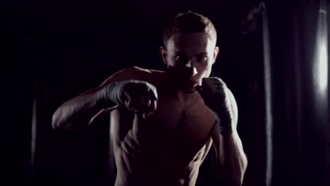 Boxeo-de-sombra-de-kickboxer-como-ejercicio-para-la-lucha.-Combate-entrenamiento-de-perforación.-Boxeo-en-la-oscuridad.-Joven-boxeador-entrenando-en-el-gimnasio