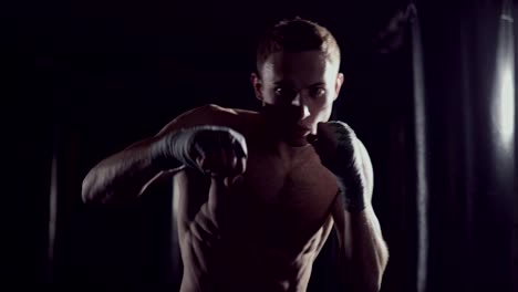 Kickboxer-shadow-boxing-as-exercise-for-the-fight.-Fighter-training-punching.-Boxing-in-the-darknes.-Young-boxer-training-in-the-gym