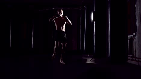 Kickboxer-shadow-boxing-as-exercise-for-the-fight.-Fighter-training-punching.-Boxing-in-the-darknes.-Young-boxer-training-in-the-gym