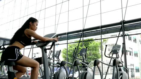 young-woman-execute-exercise-in-fitness-center.-female-athlete-riding-stationary-bicycle-in-gym.-sporty-asian-girl-working-out-in-health-club.