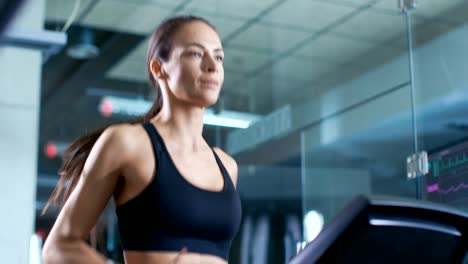 Beautiful-Woman-Athlete-Wearing-Sport-Bra,-Walks-on-a-Treadmill,-Training-Exercise.-In-the-Background-Modern-Gym/-Fitness-Club.