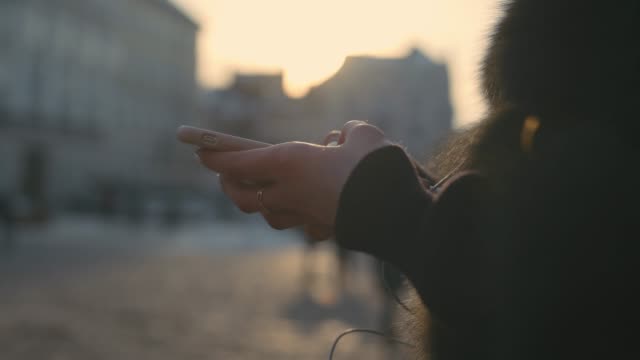 Woman-hands-using-touchscreen-phone-outdoors-in-city