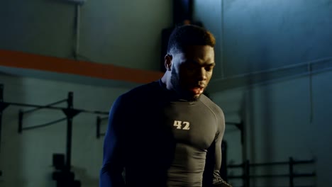 Hombre-negro-fuerte-levantamiento-kettlebells-en-gimnasio